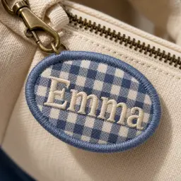 Close-up of a gingham name keychain with satin-stitched lettering