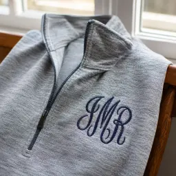 Heather grey quarter-zip with a navy satin-stitch monogram on the chest