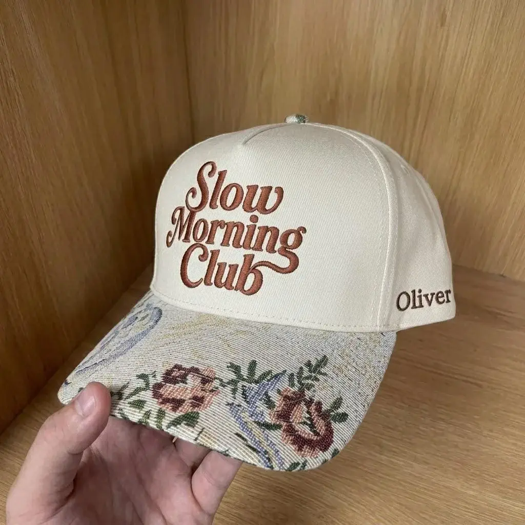 Cream cap with floral tapestry brim and embroidered text